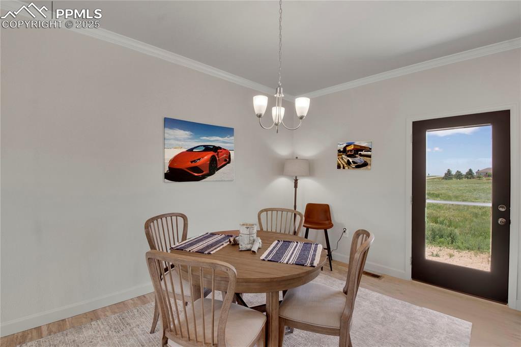 Image 11 of 25: Dining room featuring light wood-style floors, crown molding, and a chandel