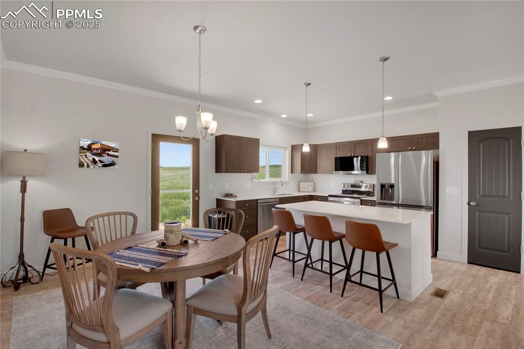 Image 12 of 25: Dining area featuring ornamental molding, light wood finished floors, and r