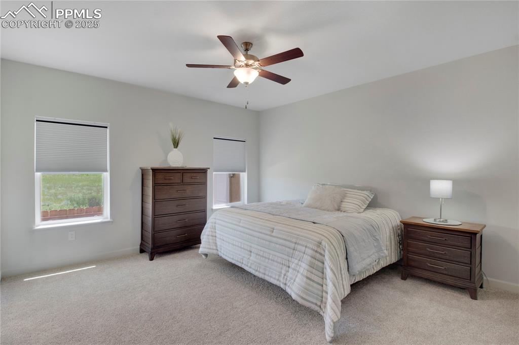 Image 14 of 25: Bedroom with light carpet and a ceiling fan