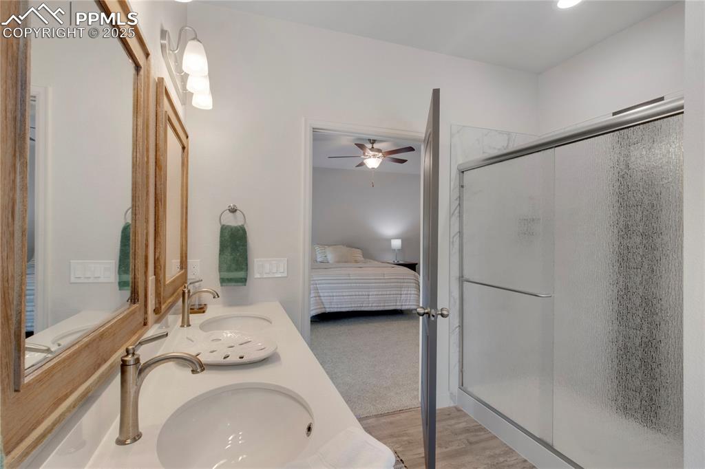 Image 19 of 25: Ensuite bathroom with a shower stall, a ceiling fan, double vanity, and woo