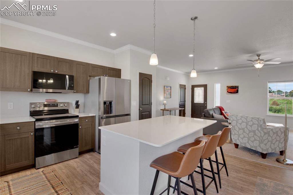 Image 8 of 25: Kitchen featuring appliances with stainless steel finishes, light wood-styl