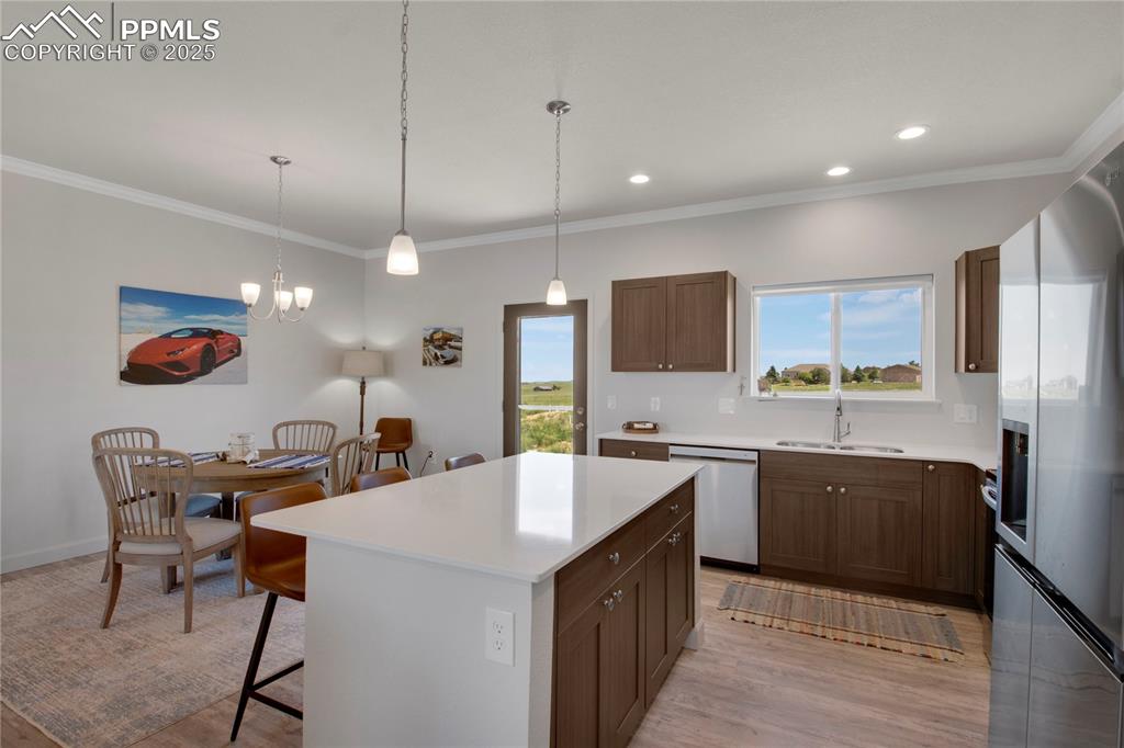 Image 9 of 25: Kitchen with stainless steel appliances, a kitchen bar, light countertops,