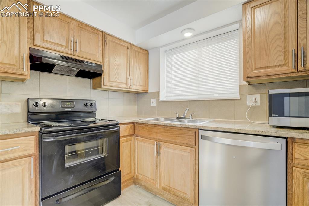 Image 26 of 42: Kitchen with stainless steel appliances, backsplash, under cabinet range ho