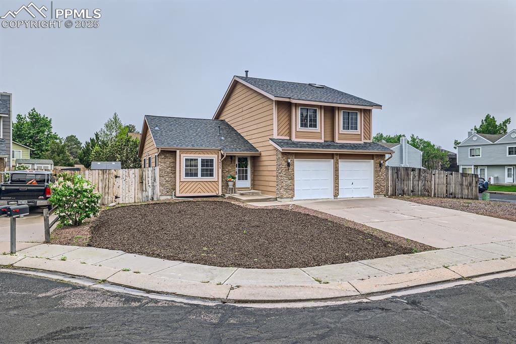 Caption: Traditional home with roof with shingles, concrete driveway, an attached garage, and stone siding