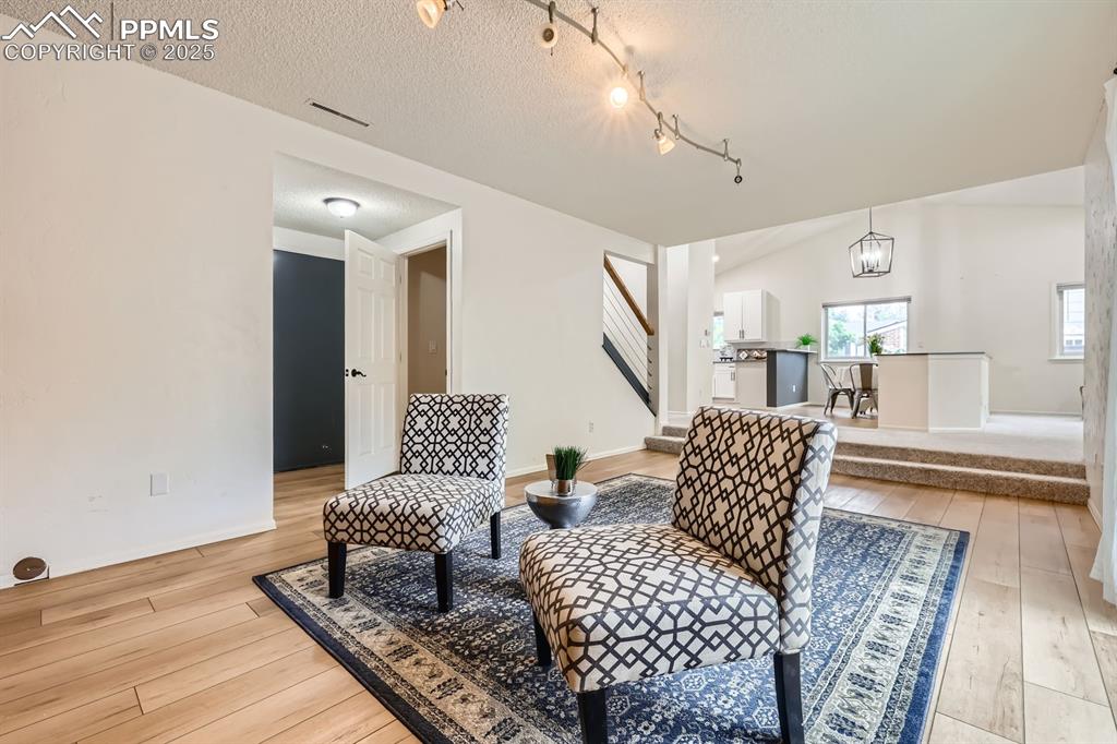 Image 13 of 28: Sitting room featuring light wood-type flooring, stairs, a textured ceiling