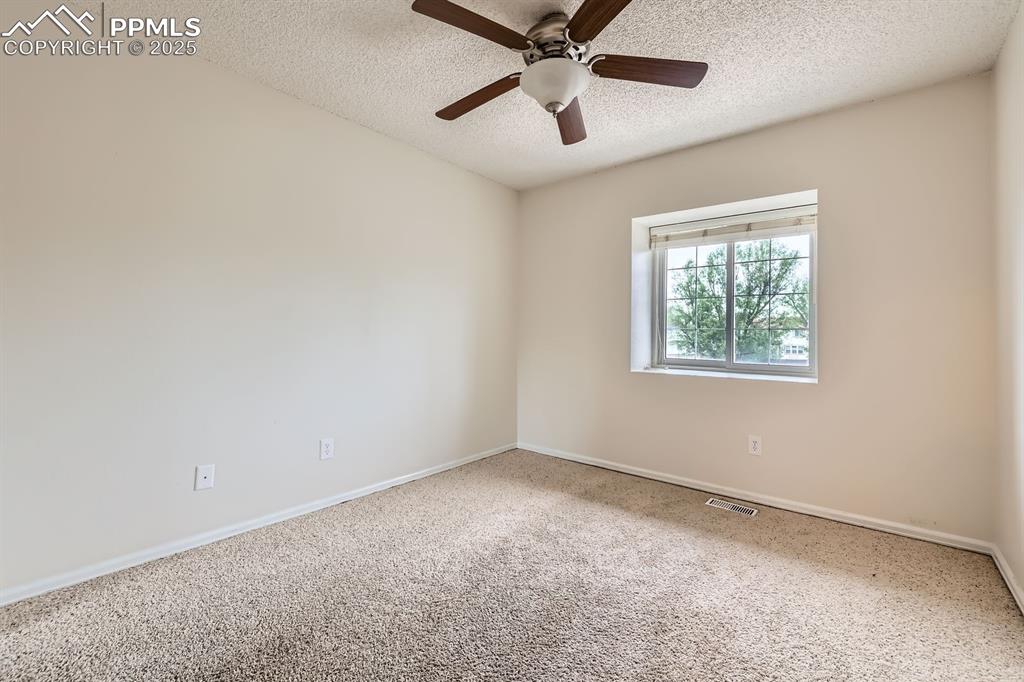 Image 21 of 28: Carpeted empty room featuring a textured ceiling and ceiling fan