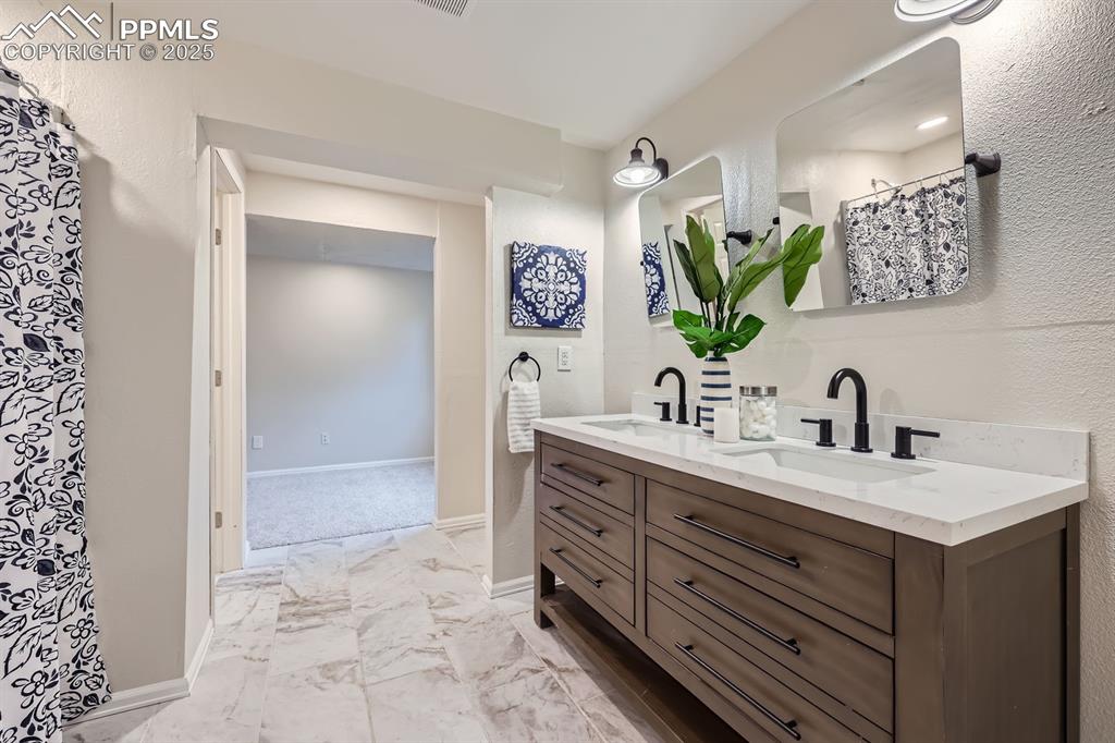 Image 24 of 28: Full bathroom featuring double vanity, marble finish floors, and a textured