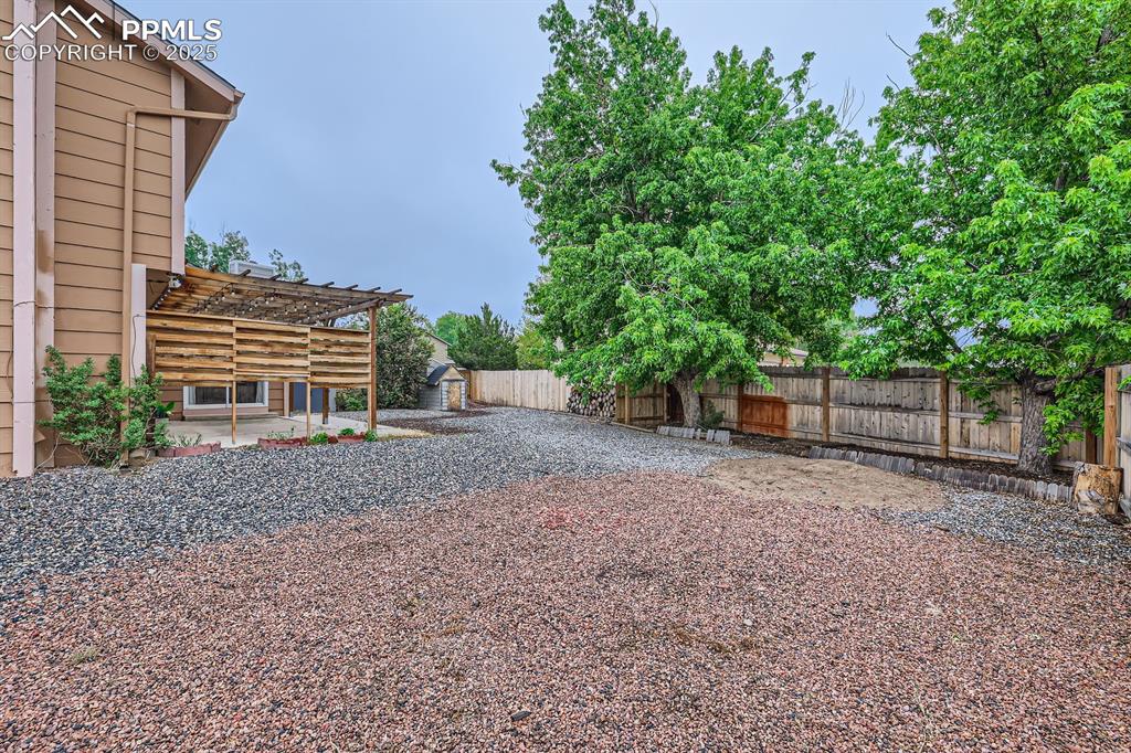 Image 28 of 28: Fenced backyard with a patio area, a pergola, and a storage shed