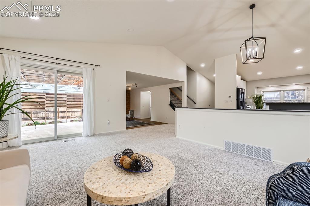 Image 6 of 28: Living area with carpet, vaulted ceiling, recessed lighting, a chandelier,