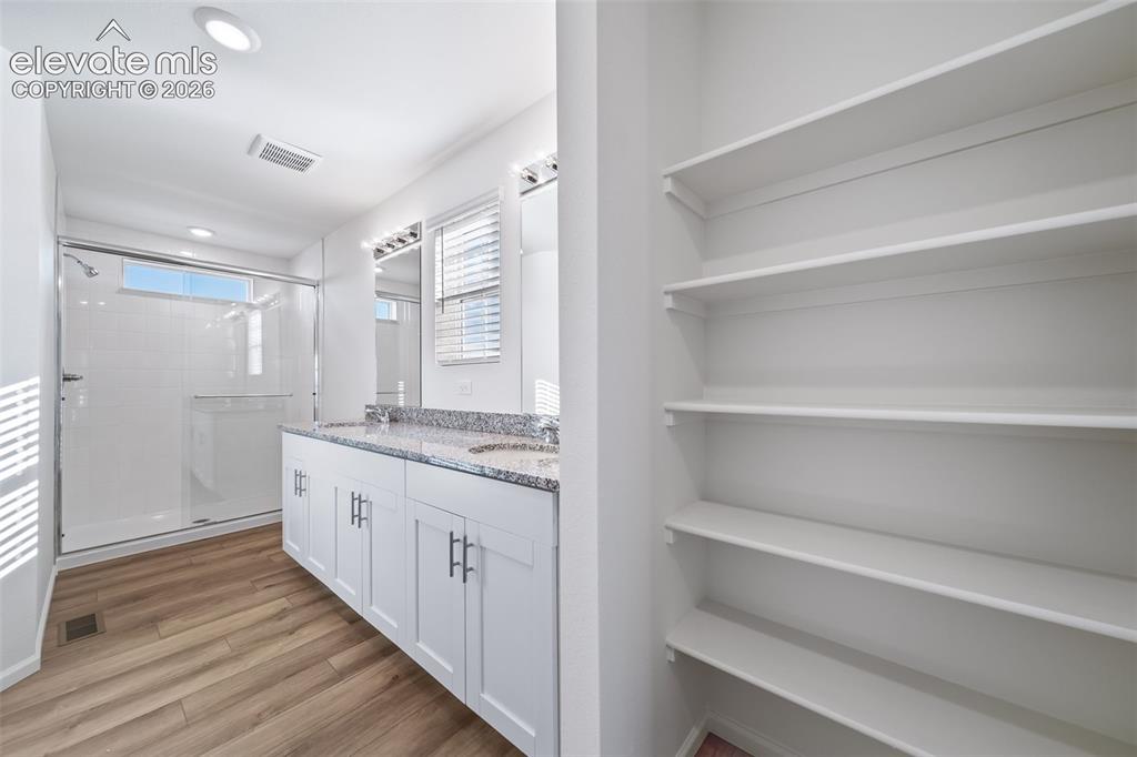 Image 10 of 15: Bathroom featuring a dual vanity with a speckled countertop, modern white c
