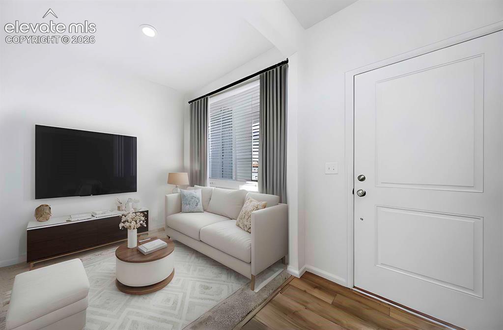 Image 4 of 15: Bright living area featuring wood-finish flooring, a contemporary white ent