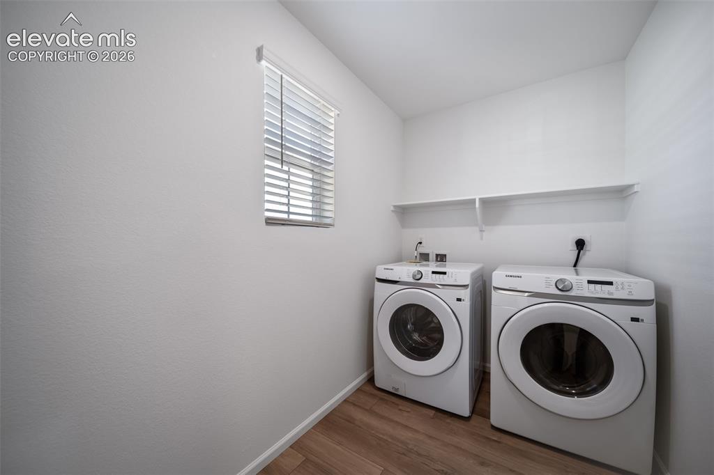 Image 9 of 15: Laundry area featuring wood-finish flooring, a bright window with blinds, a