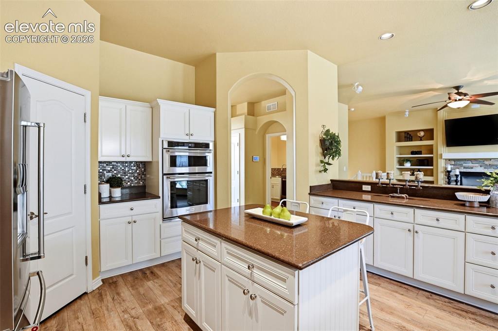 Image 17 of 41: Kitchen featuring white cabinetry, built-in double ovens, a central island 