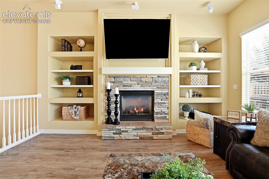 Image 24 of 41: Stacked stone fireplace with a white mantel, complemented by wood-finish fl