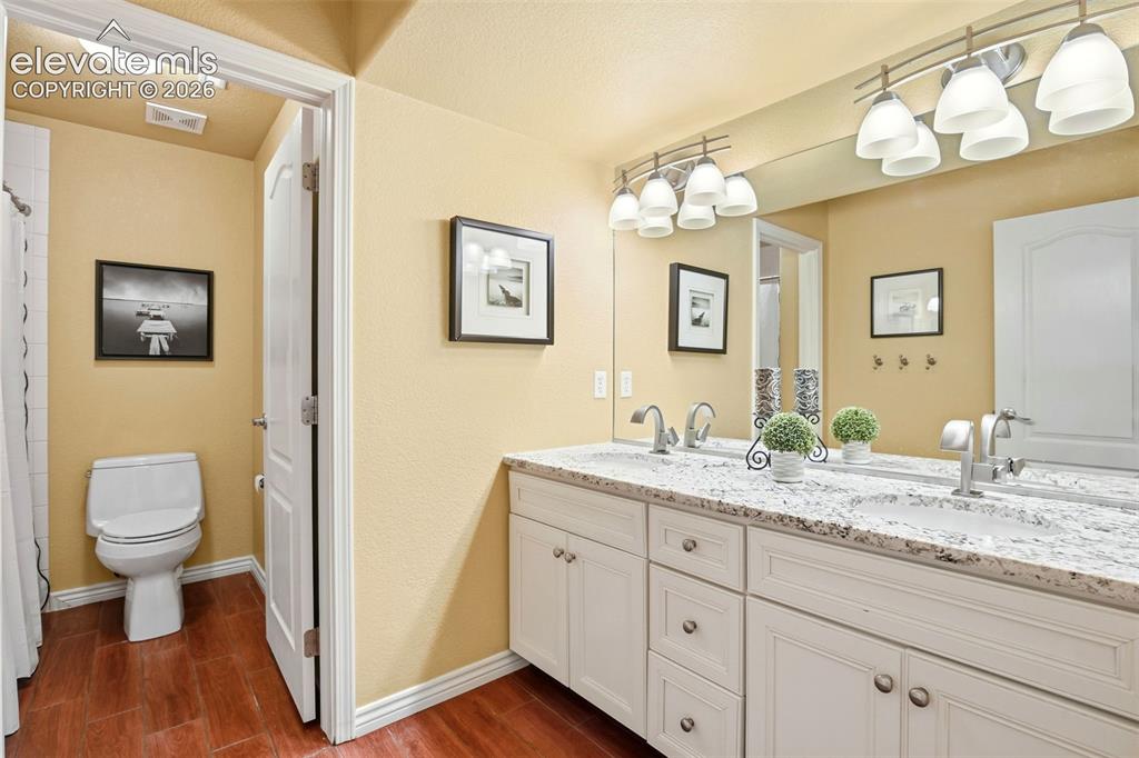 Image 32 of 41: A bright basement bathroom, with double sink vanity and a separate toilet a