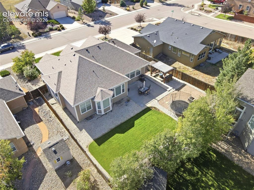 Image 38 of 41: Expansive backyard featuring a manicured lawn, concrete patio, and built-in