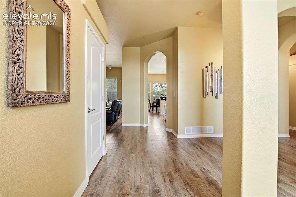 Image 5 of 41: Arched opening warm toned flooring white trim and light walls give home a c
