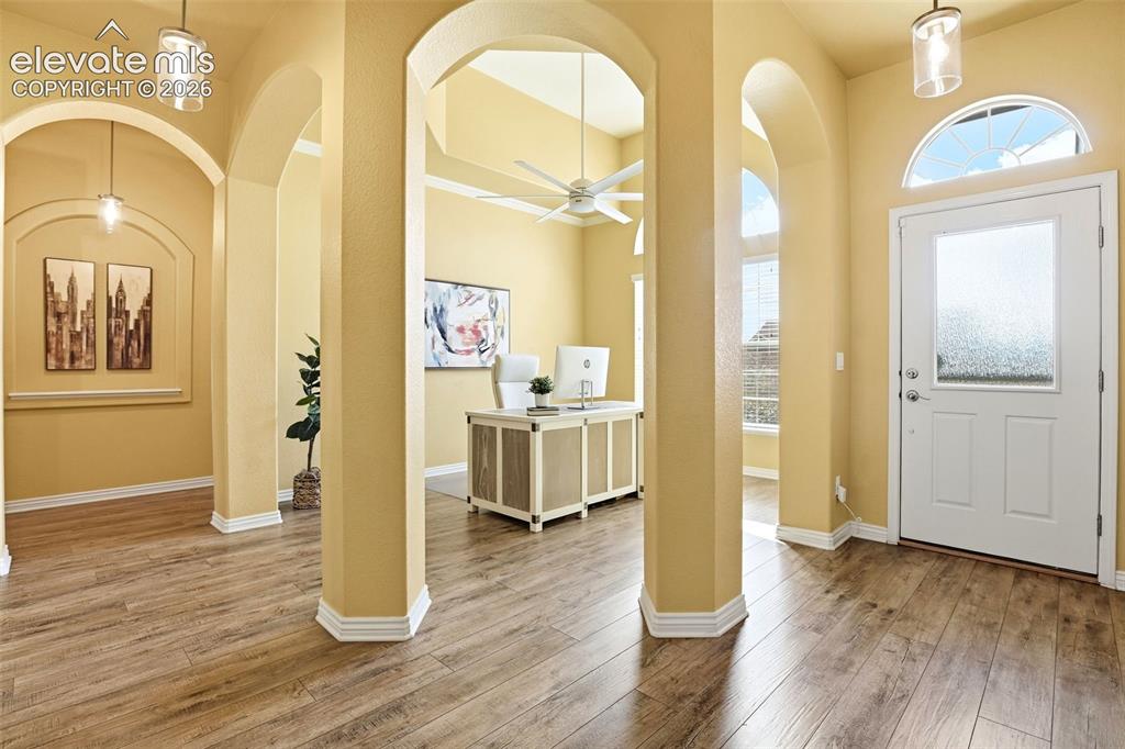 Image 6 of 41: Wood-finish flooring, arched doorways, recessed wall panels, a transom wind