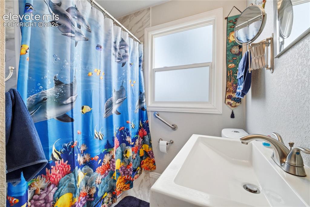 Image 13 of 22: White framed window with frosted panes, white rectangular sink with stainle