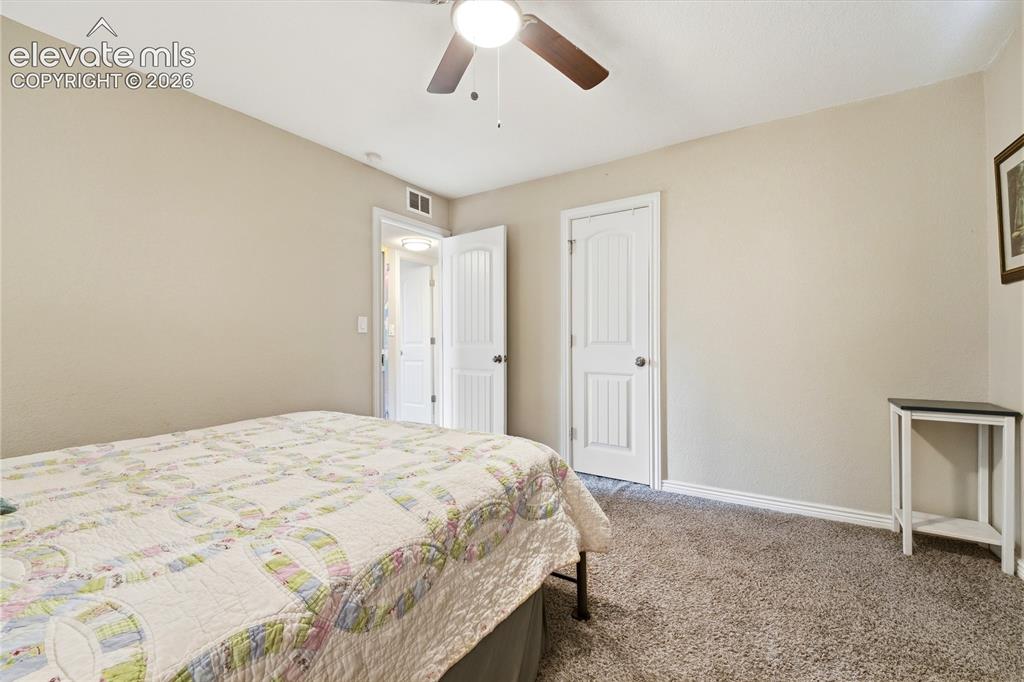 Image 16 of 22: Wall-to-wall carpeting with light-toned walls, featuring a ceiling fan with