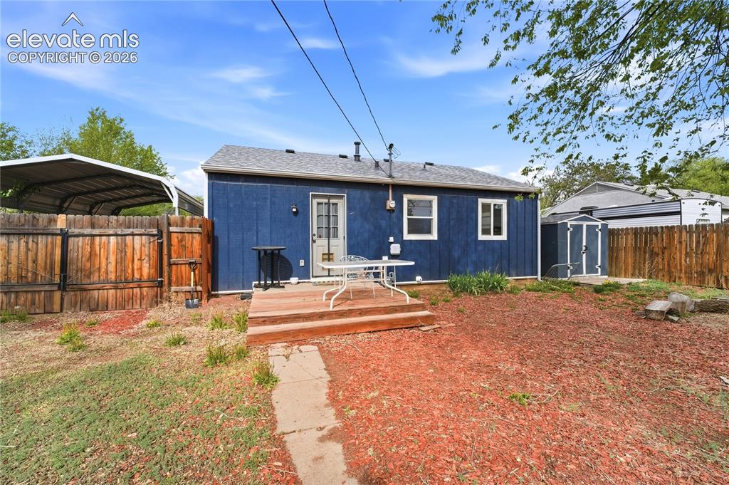 Image 17 of 22: Rear exterior featuring a wood deck with steps, a detached storage shed, an