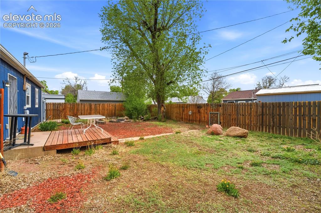 Image 18 of 22: Backyard featuring a wooden privacy fence, a raised wooden deck, a concrete