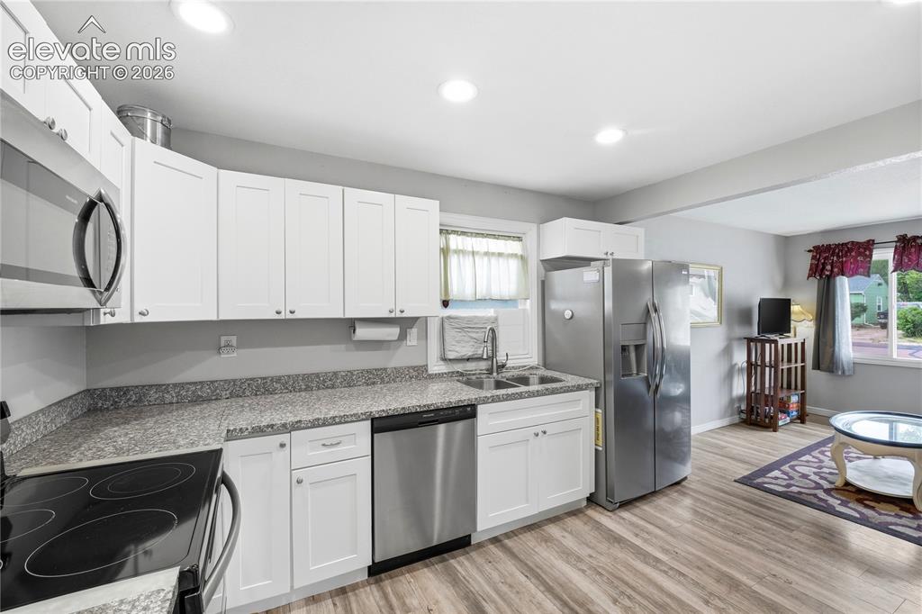 Image 7 of 22: Kitchen featuring stainless steel appliances, white cabinetry, speckled cou