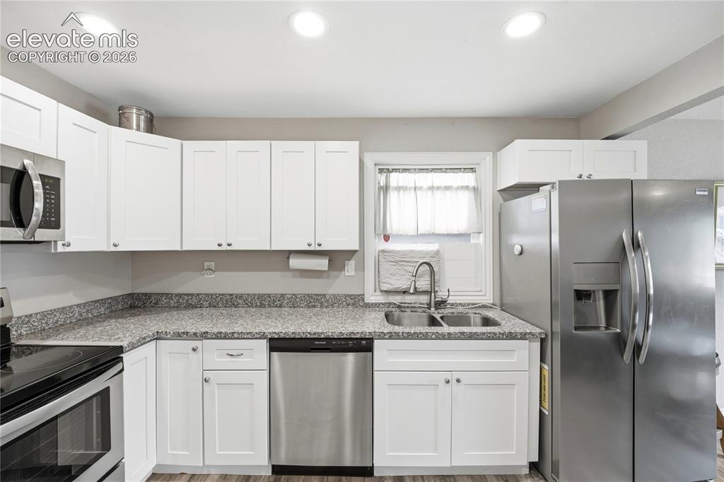 Image 8 of 22: White cabinetry with stainless steel appliances, granite-look countertops,