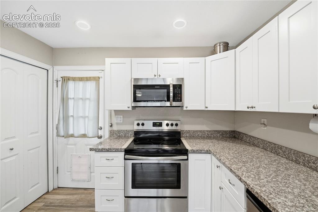 Image 9 of 22: White shaker cabinetry with stainless steel appliances, granite-style count