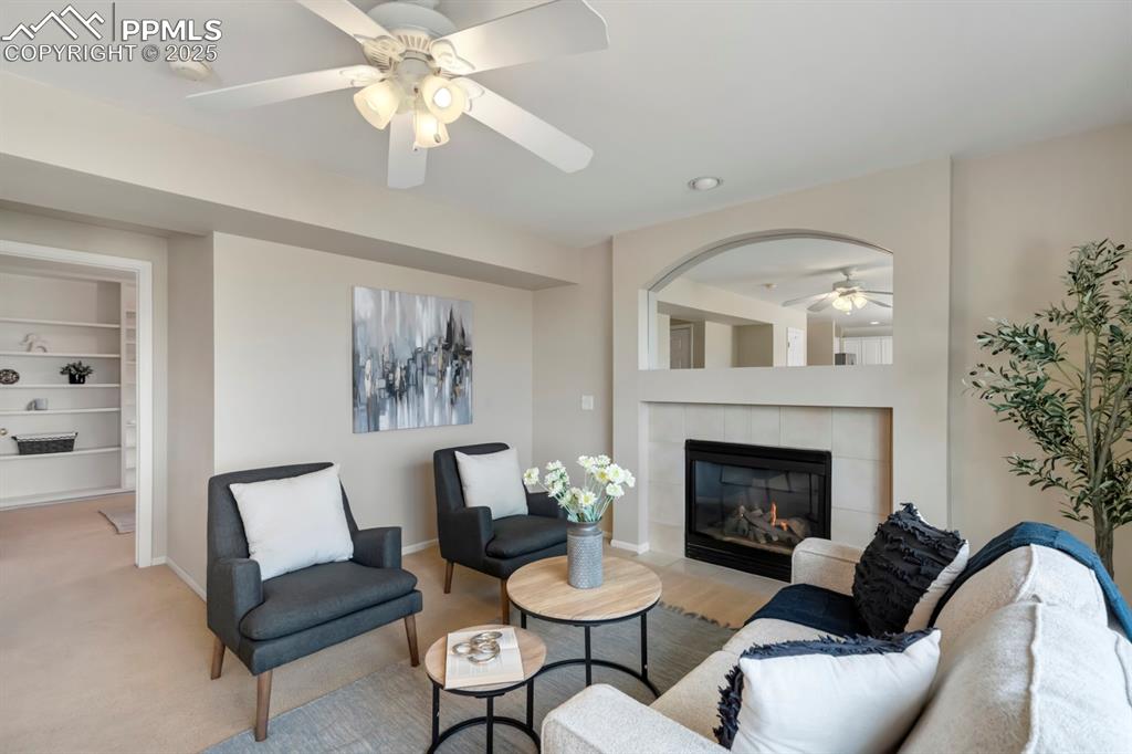 Image 10 of 24: Living room featuring ceiling fan, a tile fireplace, carpet flooring, and b