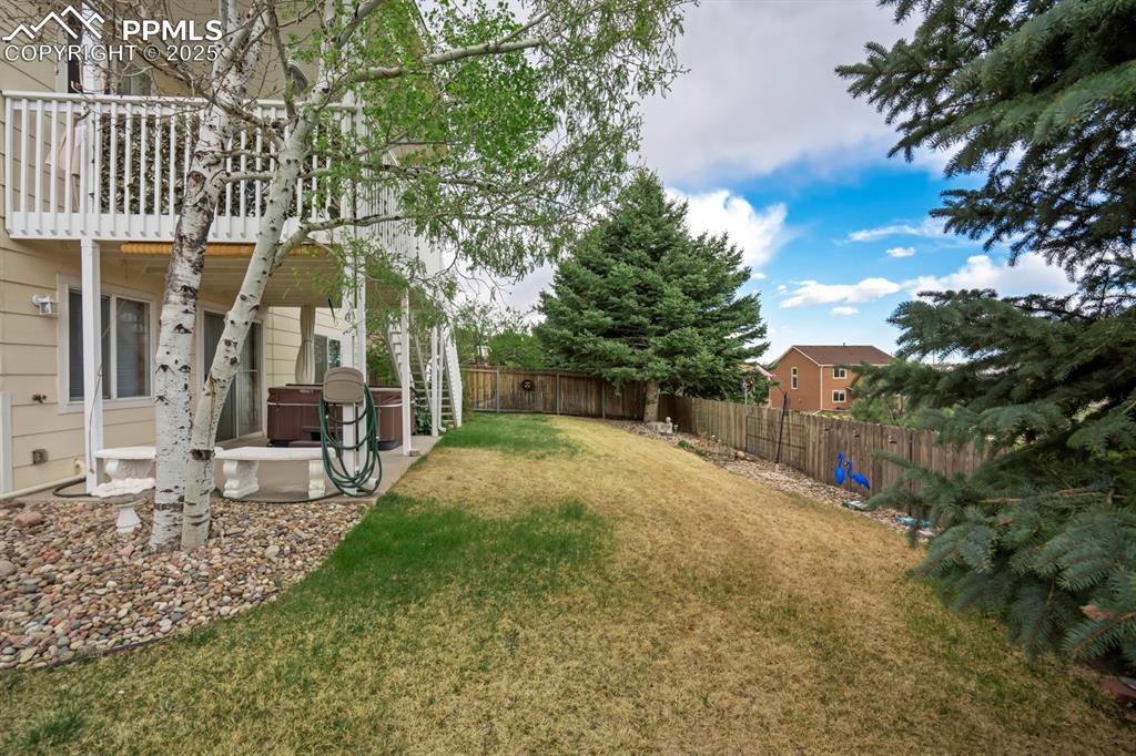 Image 18 of 24: Fenced backyard with a patio area and a balcony