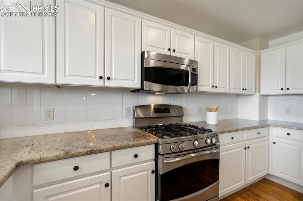 Image 5 of 24: Kitchen with appliances with stainless steel finishes, white cabinets, ligh
