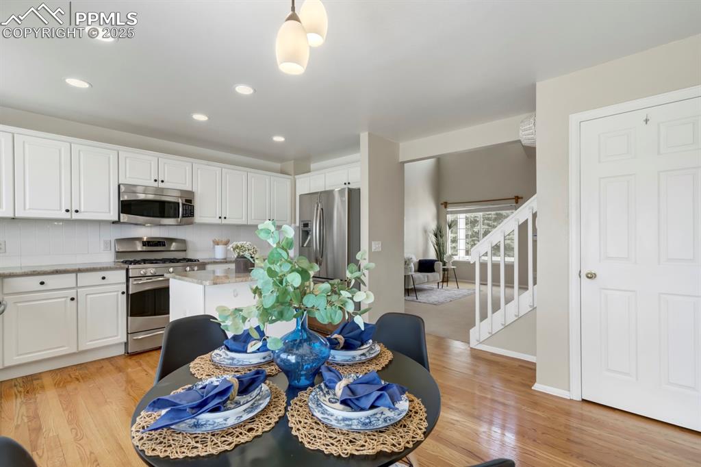 Image 8 of 24: Dining space with light wood-type flooring, recessed lighting, and stairs