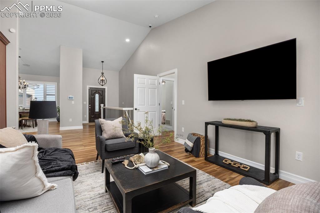 Image 11 of 49: The living room features hardwood flooring, vaulted ceilings, and a light g