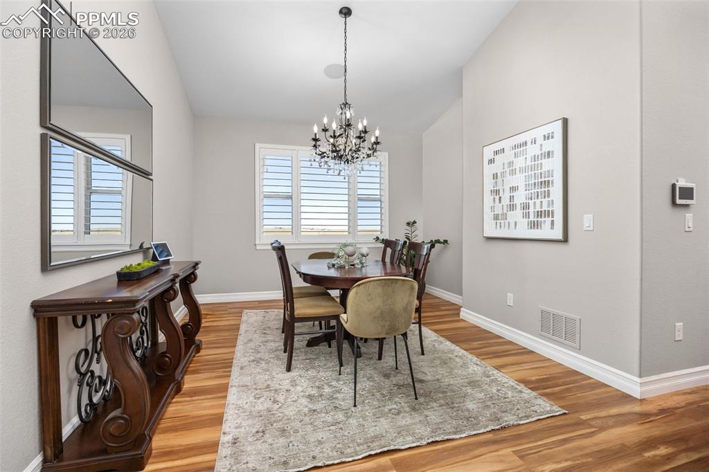 Image 15 of 49: Dining area featuring hardwood floors, a large area rug, a chandelier, and 