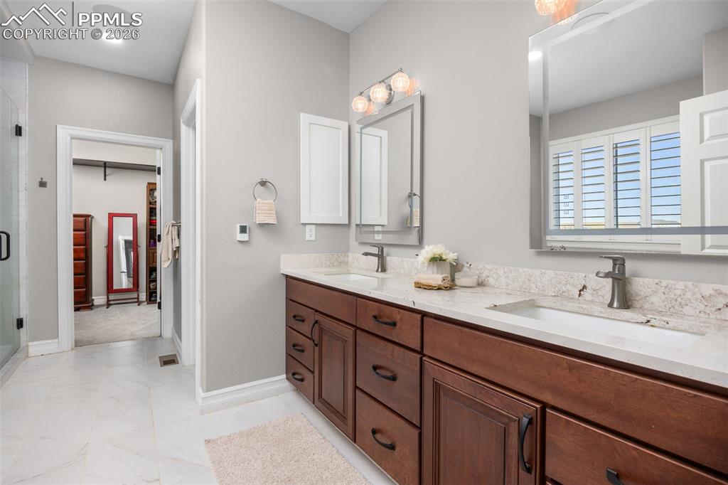 Image 18 of 49: Bathroom featuring a double vanity with wooden cabinetry, light-colored cou