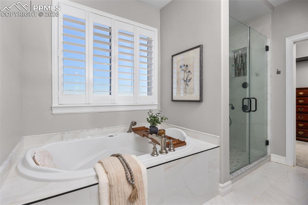 Image 19 of 49: Bathroom featuring a built-in bathtub with a white marble surround, a windo