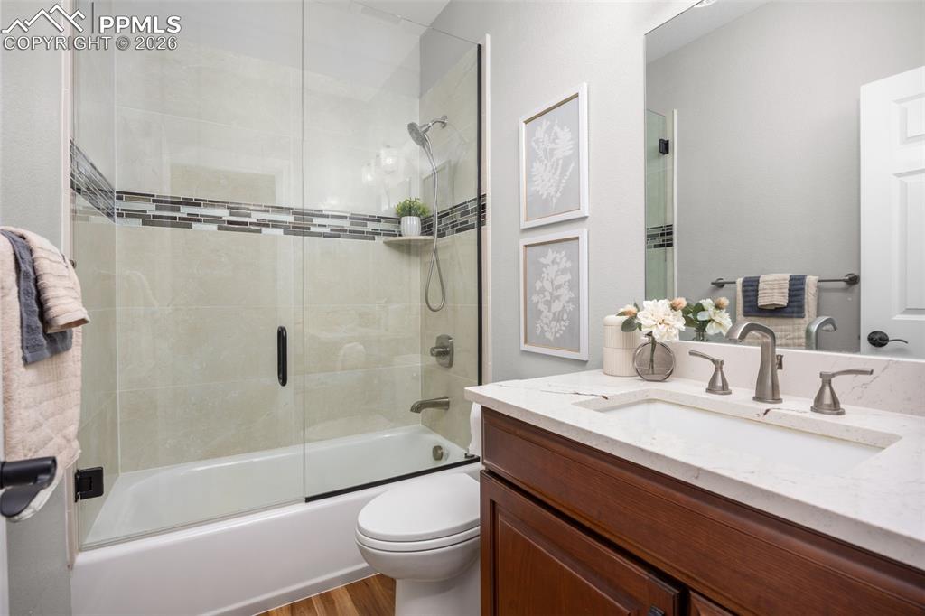 Image 22 of 49: Bathroom featuring a bathtub with glass sliding doors, tiled surround with 