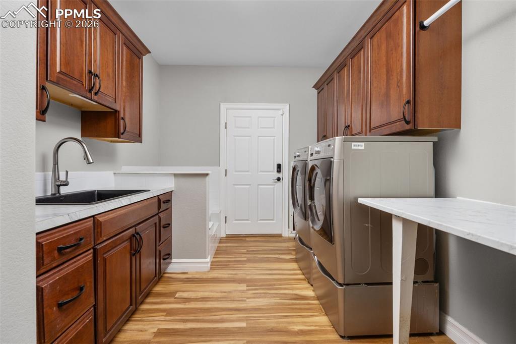 Image 23 of 49: This laundry room features ample storage with dark wood cabinetry, a utilit