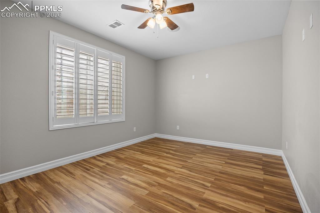 Image 32 of 49: This room features light-toned walls, wood-style flooring, a window with wh