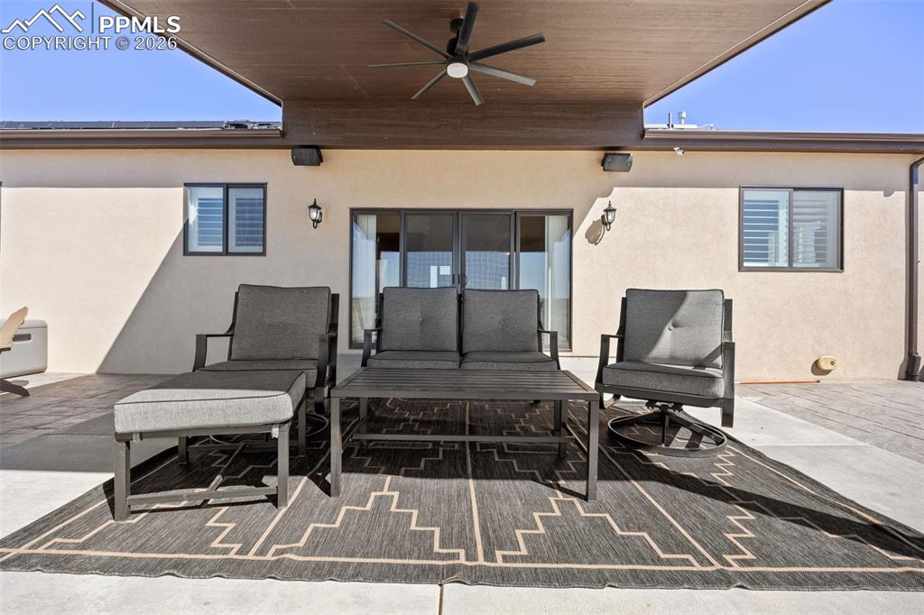 Image 34 of 49: The property features a covered patio area with a ceiling fan, providing a 