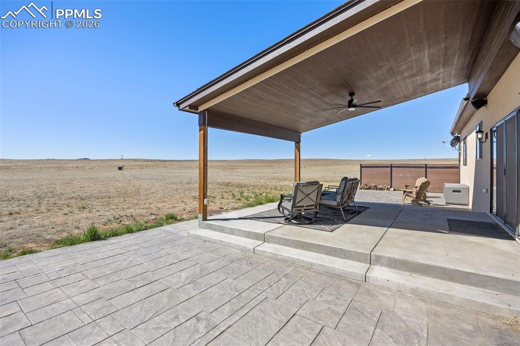 Image 35 of 49: Expansive concrete patio with a covered outdoor area, featuring a ceiling f