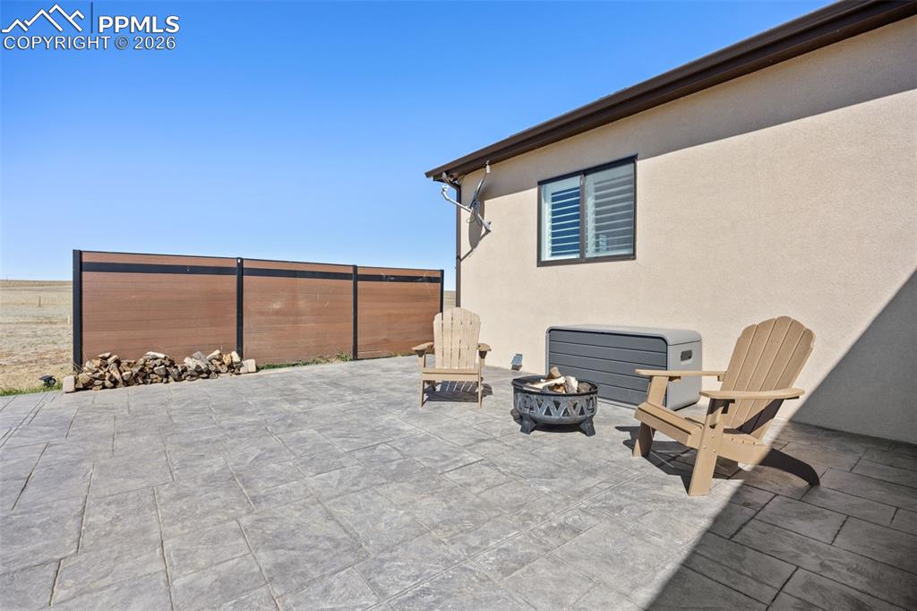 Image 36 of 49: The property features a patio with stamped concrete flooring, a fire pit, a