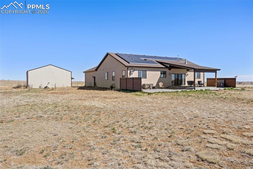 Image 39 of 49: The property features a stucco exterior, a covered patio, and a separate la