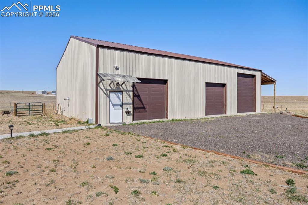 Image 41 of 49: The property features a large metal building with a brown roof and three ro