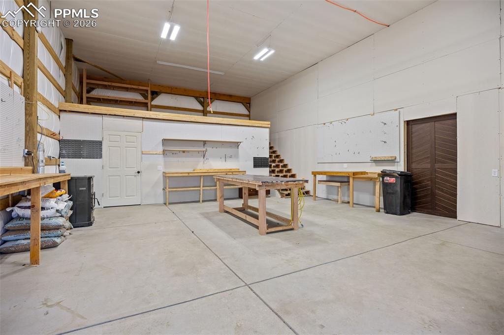 Image 42 of 49: Spacious interior with concrete flooring, high ceilings, and exposed wooden