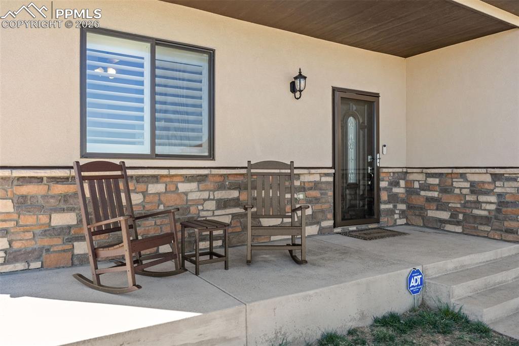 Image 5 of 49: The property features a covered front porch with stone facade accents and a