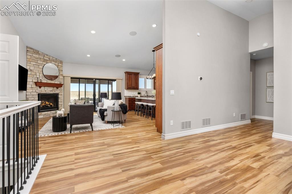 Image 7 of 49: Spacious open concept living area featuring wood-style flooring, a stone fi