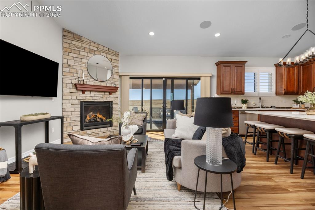 Image 8 of 49: Living room featuring a stacked stone fireplace with a wooden mantel, hardw