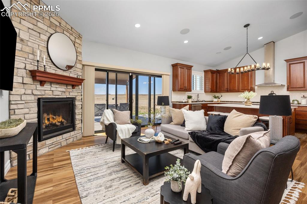 Image 9 of 49: The spacious living area features hardwood floors, a stone fireplace, and s